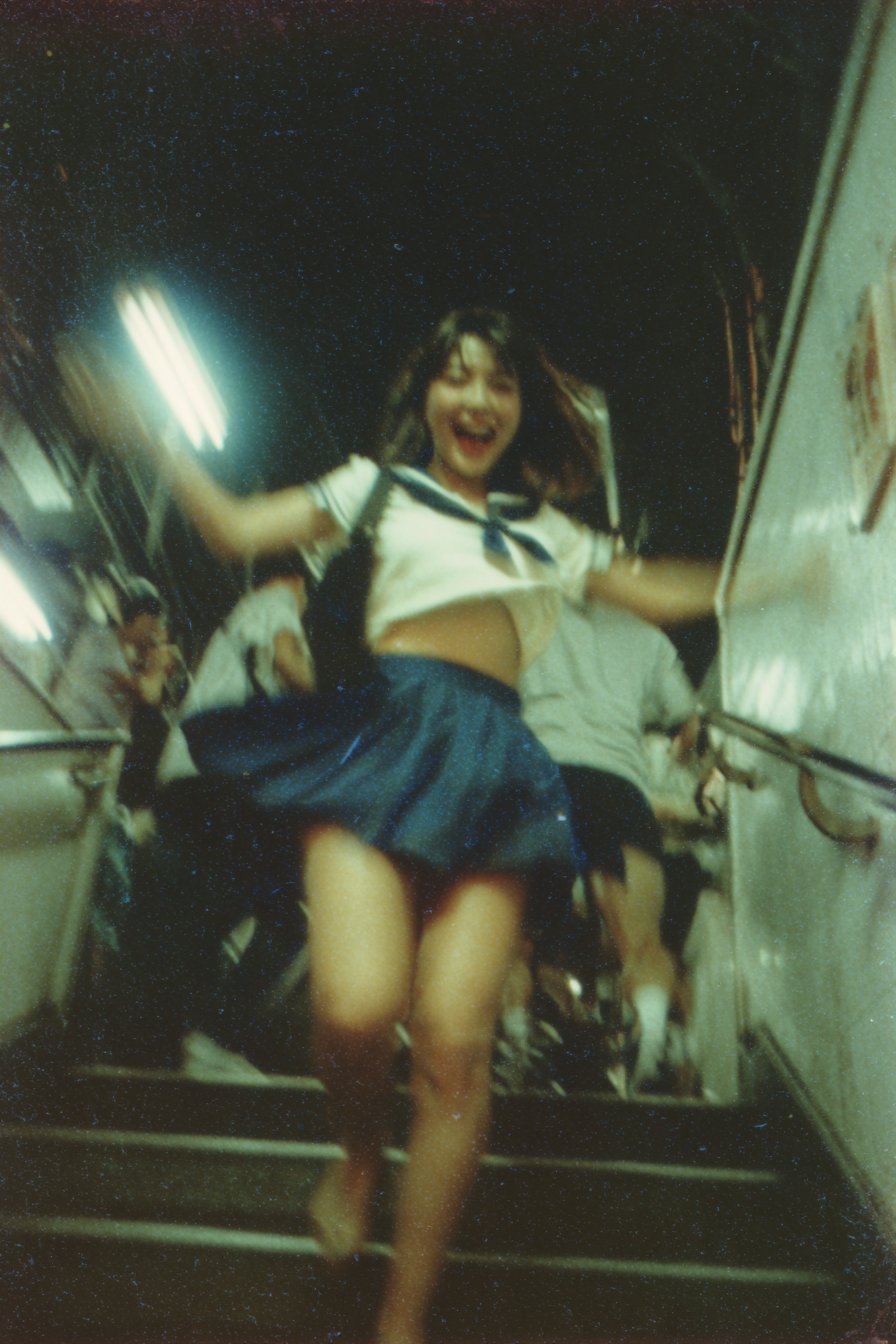 即时相机拍摄的东京夏季夜晚地铁楼梯上一名日本高中女生